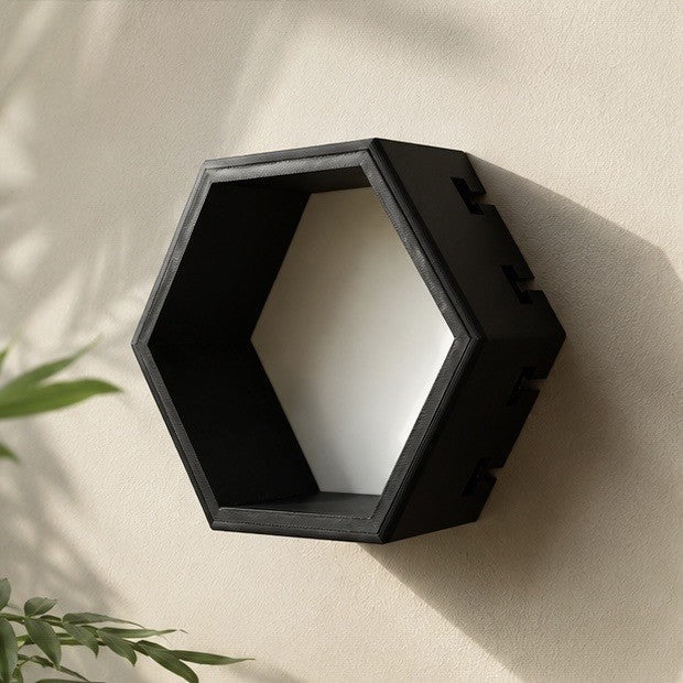 Hexagonal wall shelf in matte black with white back panel on a cream wall